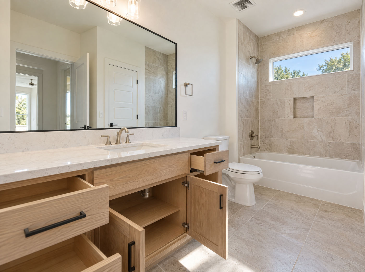 A spotless empty bathroom with a polished vanity, clear mirror and gleaming tile